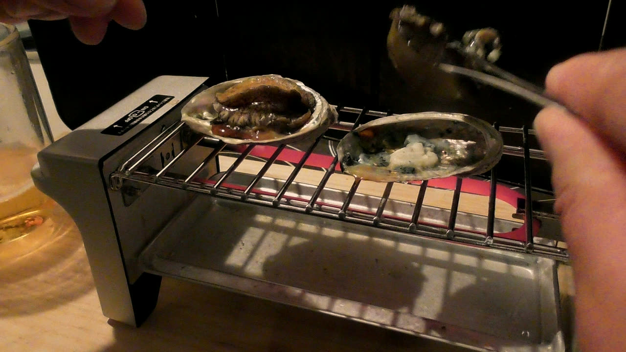 トングで鮑の身をひっくり返しているところ