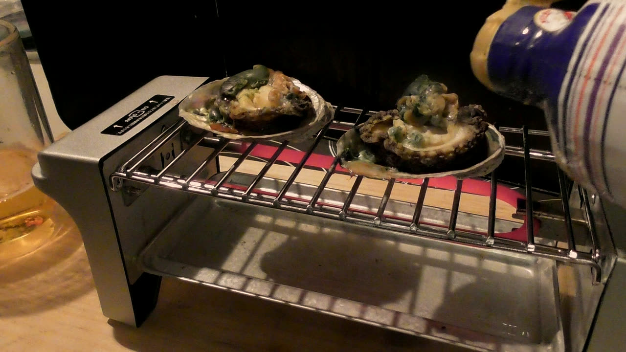 網の上の鮑に、醤油をたらしているところ