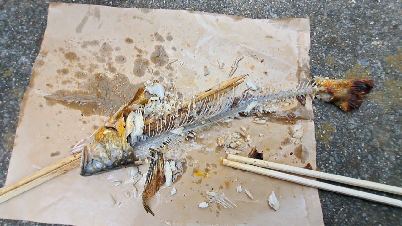 紙の上で骨だけになった鮎と割り箸