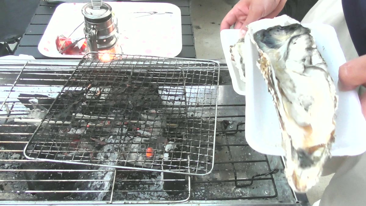 殻付き牡蠣を炭の上に置くところ