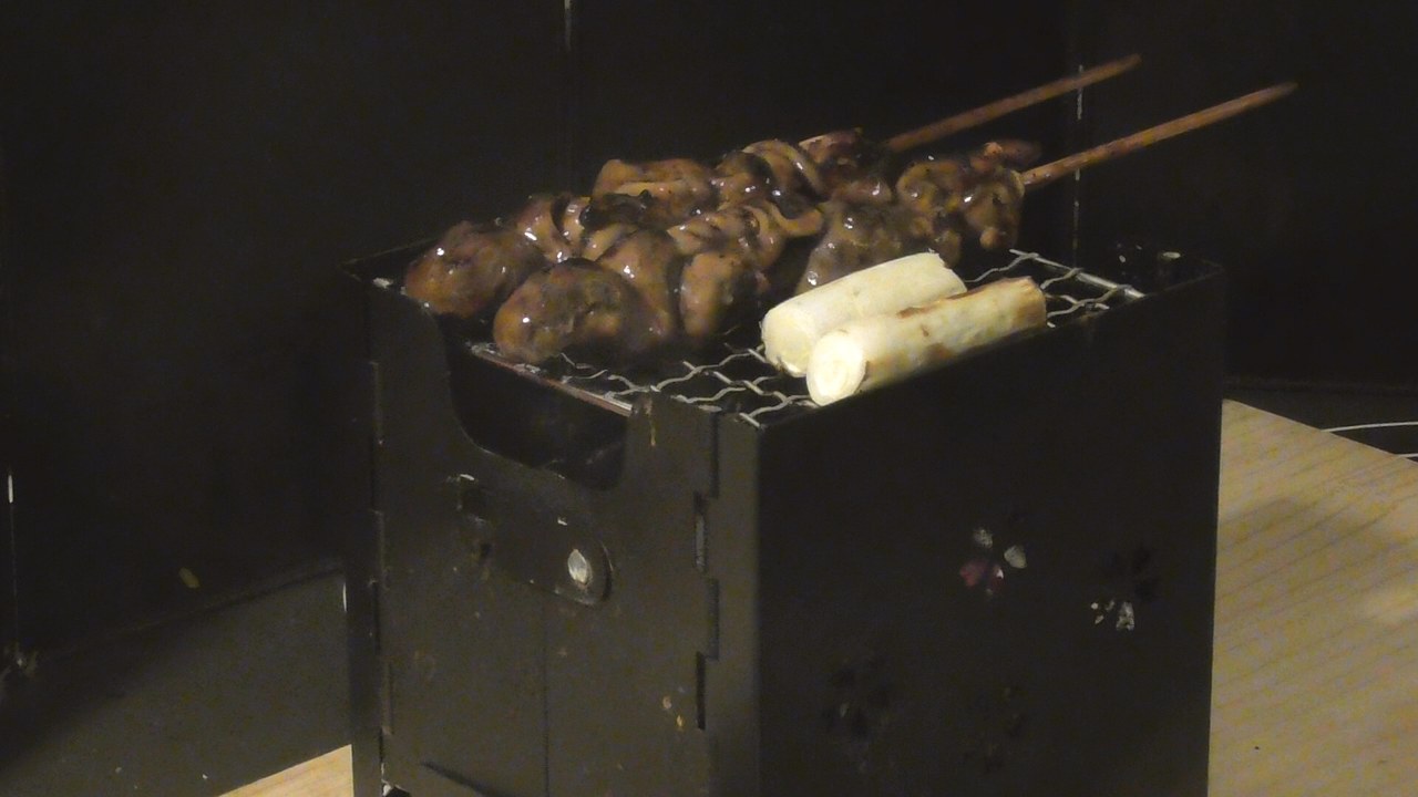 網の上で、うなぎの肝串2本と長ネギを焼いているところ