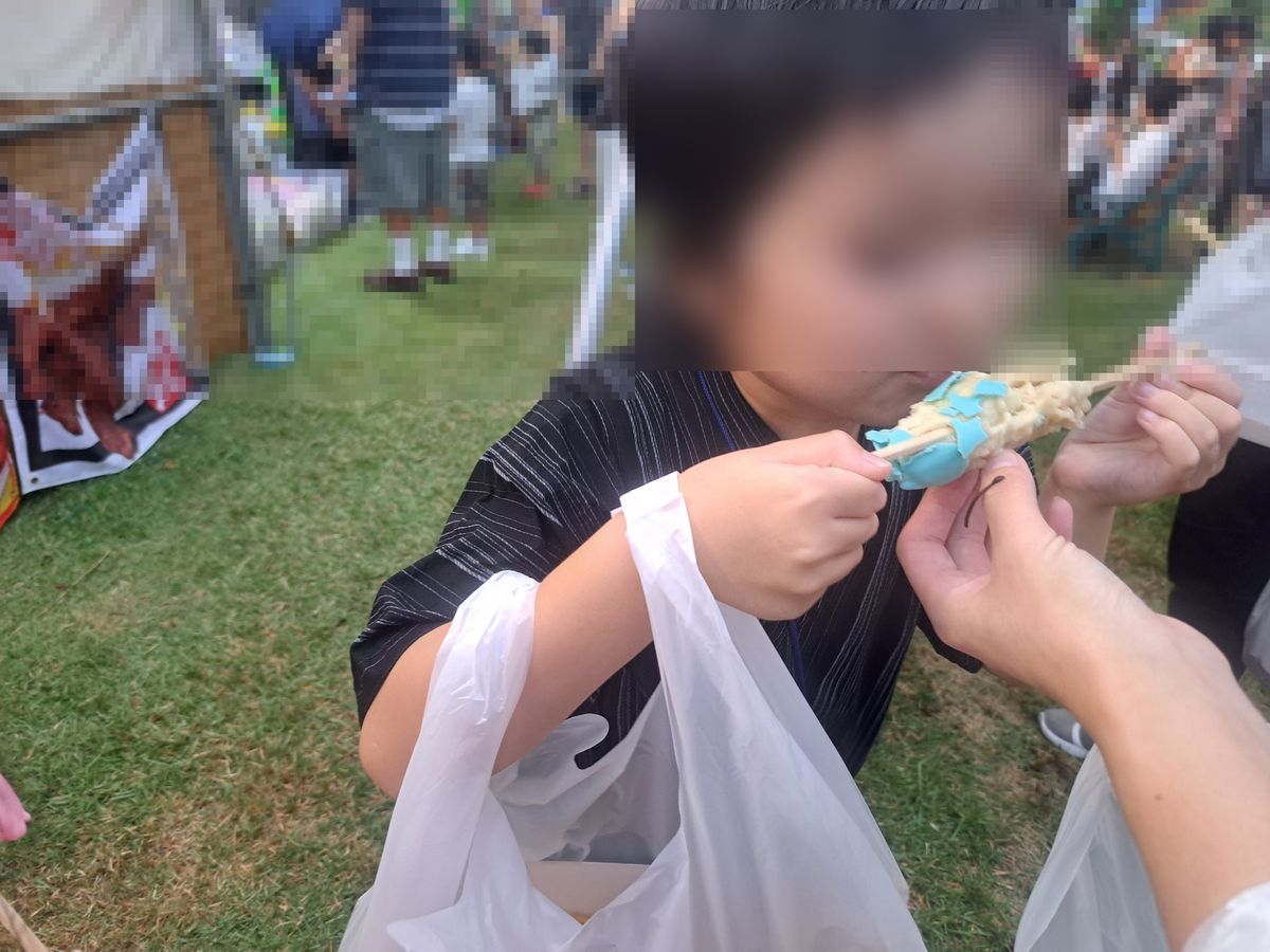 屋台で買ったたこ焼きを食べる子ども