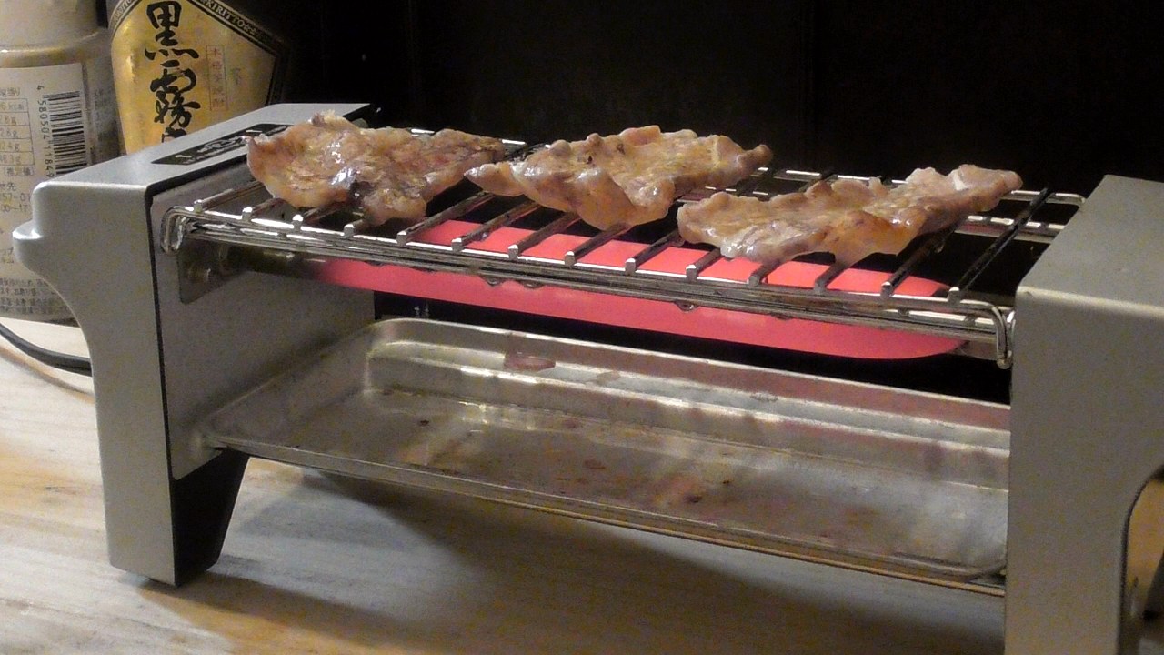 焼き鳥用の卓上電気グリルの網の上で、赤く光るヒーターに焼かれている牛バラカルビ3枚