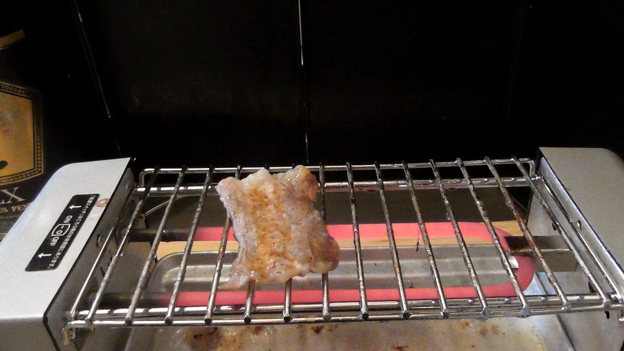焼き鳥グリルの網の上に、焼けたカルビが1枚だけ残っているところ