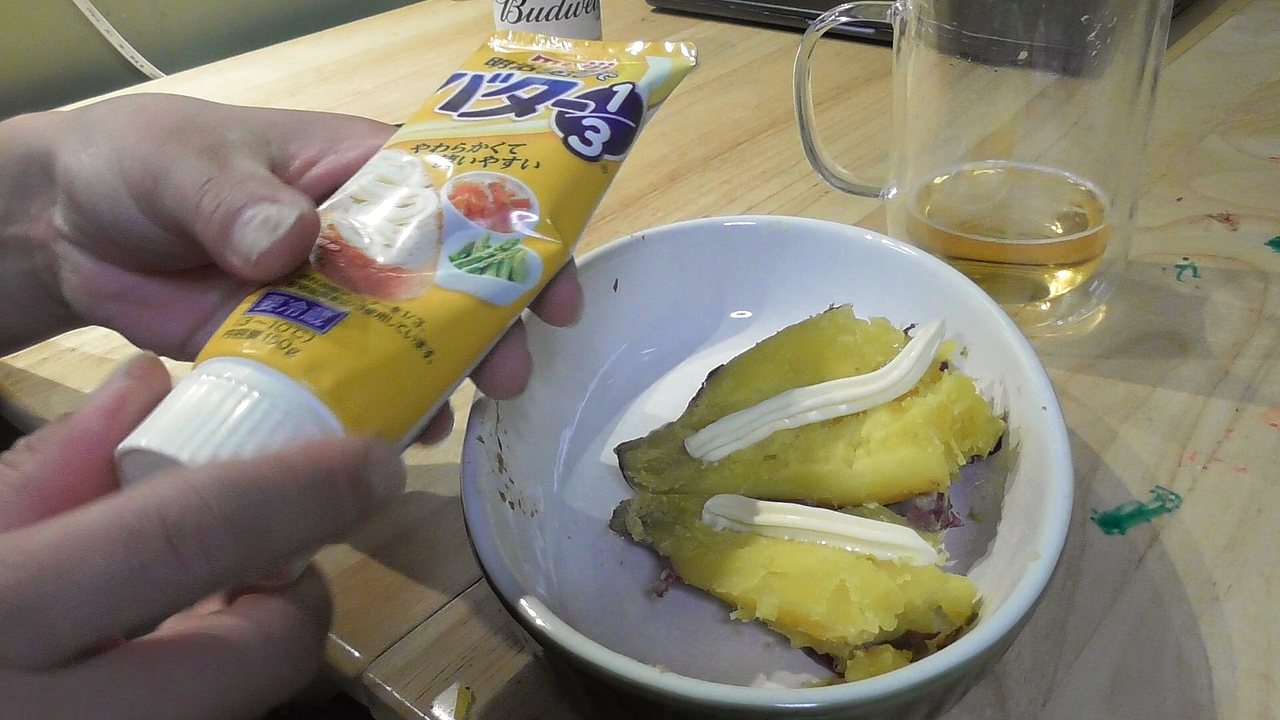 焼き芋にチューブのバターをしぼっているところ